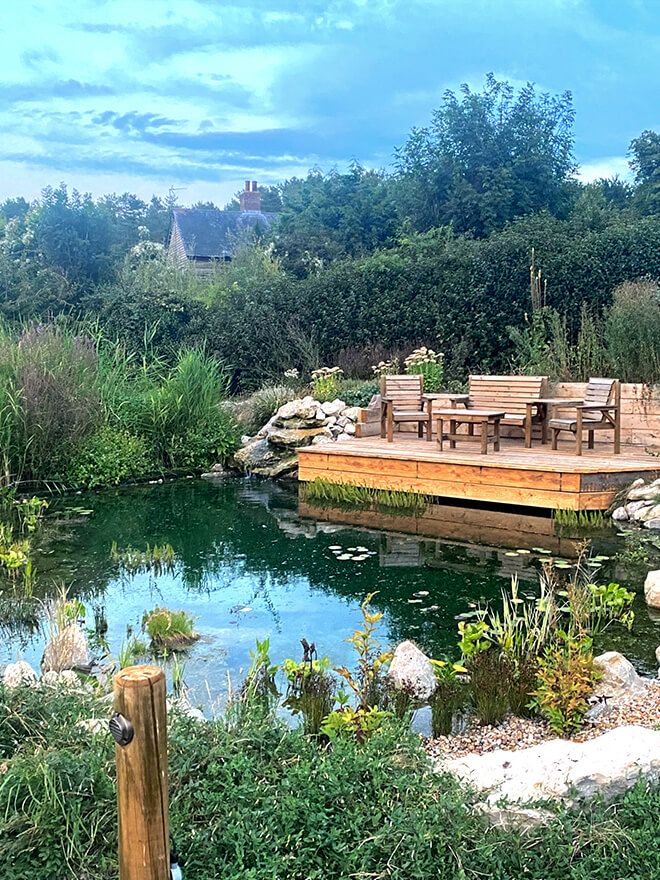 Natural swim pond with a floating timber deck, table and chairs