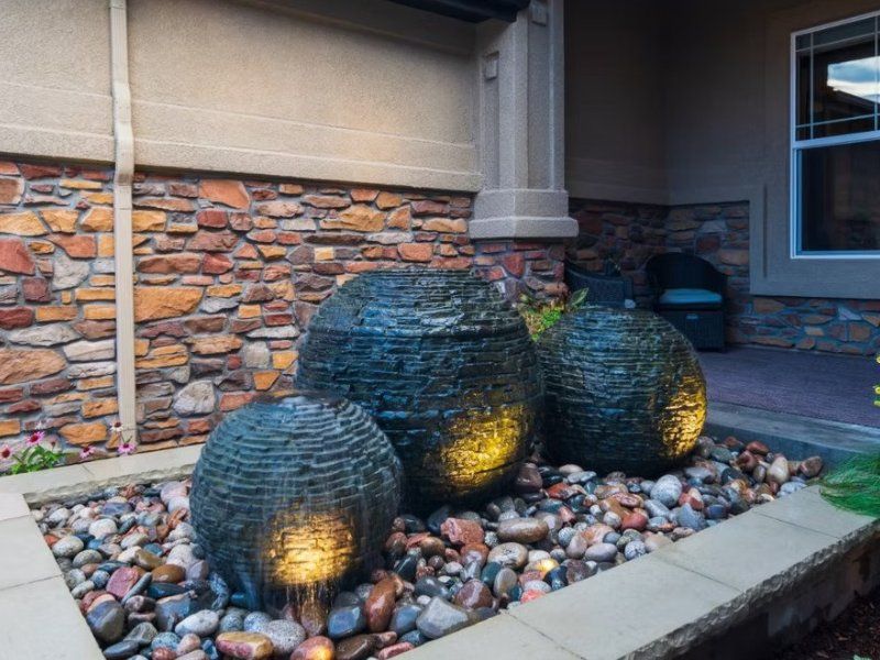 Three stacked slate spheres lit at dusk in a pebble bed