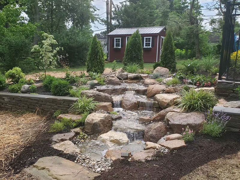 Stepped stream running through a gravel garden towards a shed